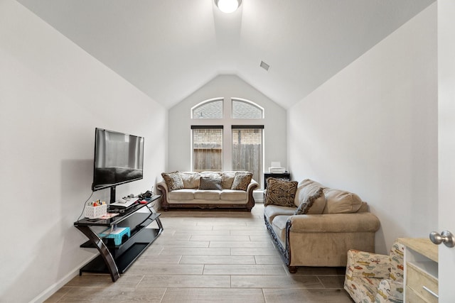 living area with lofted ceiling, visible vents, and wood finish floors
