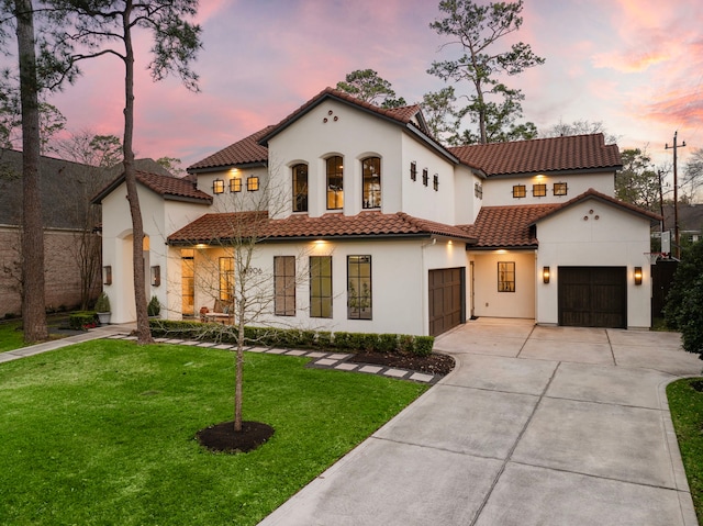 mediterranean / spanish home with a garage, stucco siding, a tiled roof, driveway, and a lawn