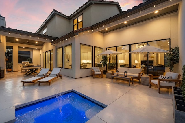 back of property with a patio area, stucco siding, a tiled roof, and an outdoor pool