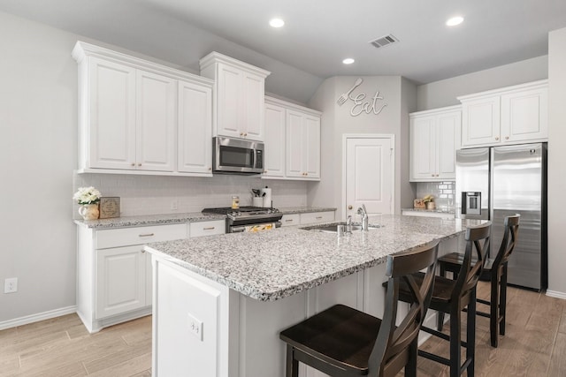 156 Buckeye Dr, Montgomery, TX 77316 - kitchen with visible vents, light wood-style flooring, tasteful backsplash, and stainless steel appliances