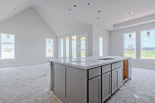 197 Peninsula Point Dr, Montgomery, TX 77356 - kitchen with an island with sink, gray cabinets, baseboards, light stone countertops, and open floor plan