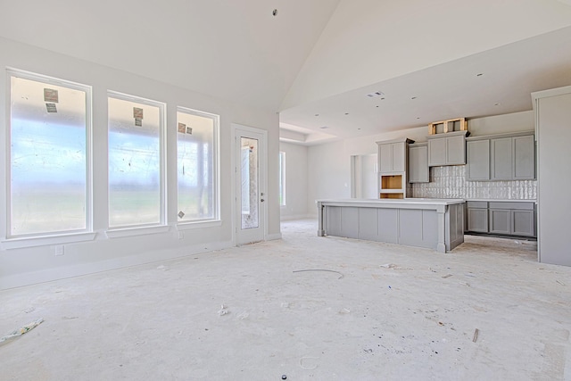 197 Peninsula Point Dr, Montgomery, TX 77356 - kitchen with gray cabinets, backsplash, lofted ceiling, a center island, and baseboards