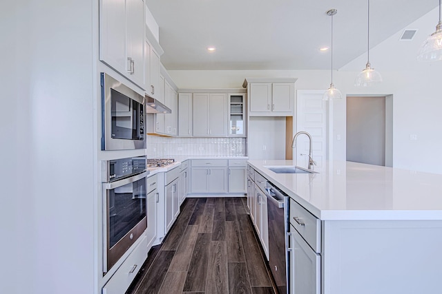 197 Peninsula Point Dr, Montgomery, TX 77356 - kitchen with stainless steel appliances, under cabinet range hood, light countertops, an island with sink, and decorative backsplash