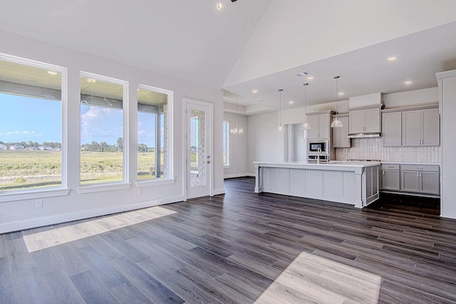 197 Peninsula Point Dr, Montgomery, TX 77356 - kitchen featuring built in microwave, light countertops, backsplash, dark wood-style flooring, and a kitchen island with sink