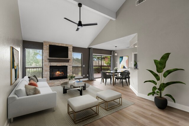 living room with wood finished floors, a ceiling fan, visible vents, beam ceiling, and a fireplace