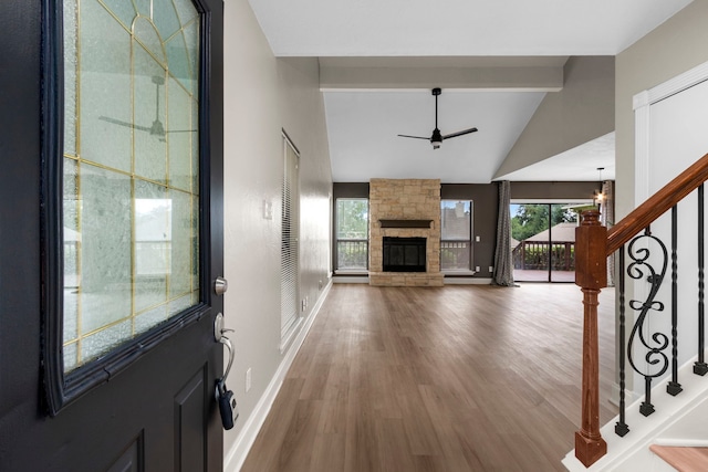 foyer featuring baseboards, stairs, a fireplace, wood finished floors, and a ceiling fan