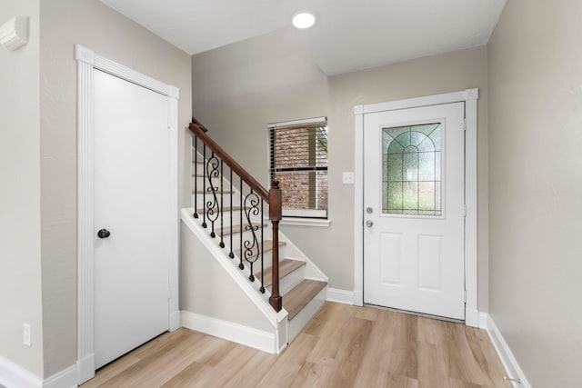 foyer with stairway, light wood-style floors, and baseboards