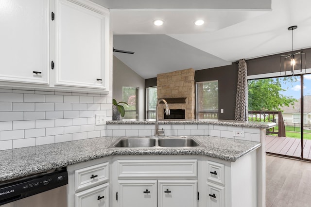 kitchen with backsplash, dishwasher, a peninsula, white cabinetry, and a sink