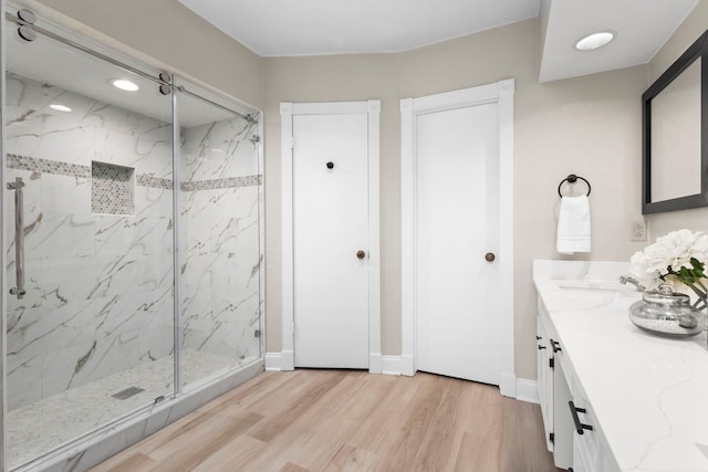 full bathroom with a marble finish shower, baseboards, and wood finished floors