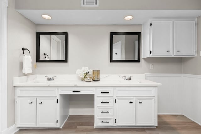 bathroom featuring a sink, visible vents, wood finished floors, and double vanity