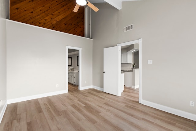 unfurnished bedroom featuring visible vents, connected bathroom, baseboards, light wood-style floors, and high vaulted ceiling