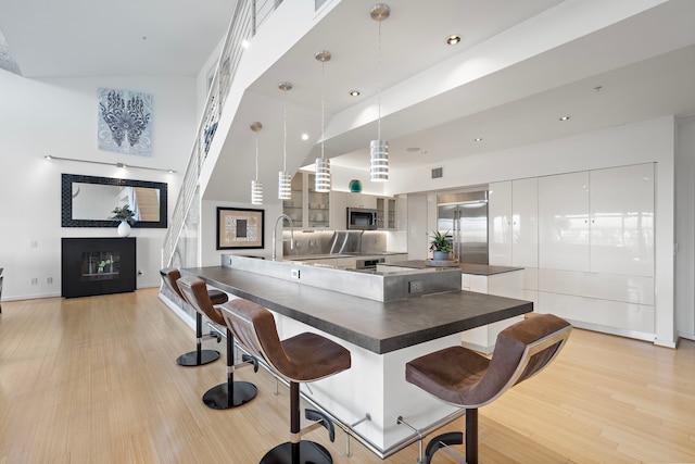 102 Quitman St Unit 405, Houston, TX 77009 - kitchen featuring a fireplace, glass insert cabinets, stainless steel appliances, dark countertops, and light wood-style floors