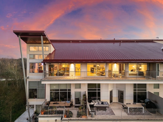 102 Quitman St Unit 405, Houston, TX 77009 - back of property at dusk with a balcony, an outdoor hangout area, a patio area, and metal roof