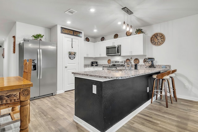 kitchen featuring visible vents, light wood-style flooring, appliances with stainless steel finishes, a peninsula, and white cabinets