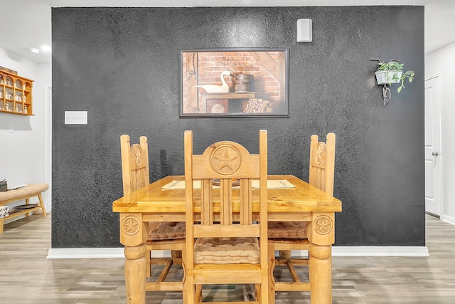 dining space with baseboards and wood finished floors