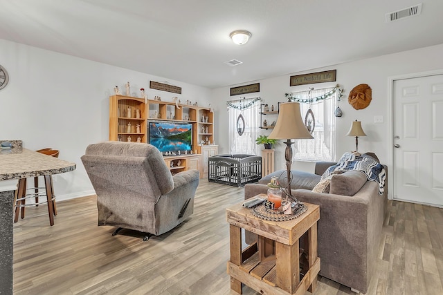 living area featuring light wood-style flooring, baseboards, and visible vents