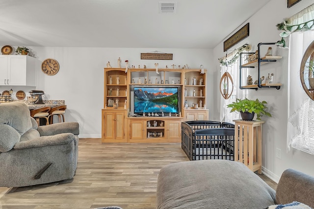 living area with light wood-type flooring, visible vents, and baseboards
