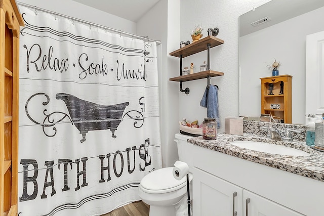 bathroom featuring visible vents, toilet, wood finished floors, a shower with shower curtain, and vanity
