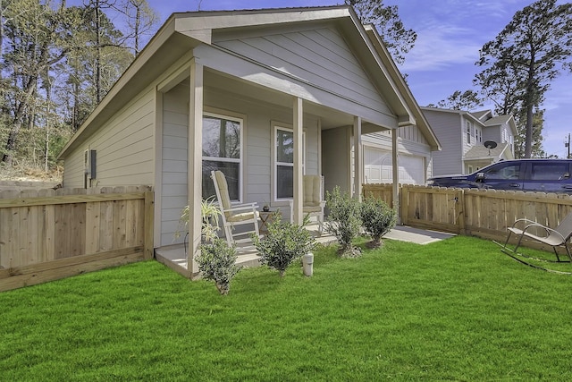 back of house with a garage, a lawn, and fence