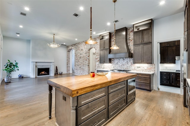 3302 Elmridge St, Houston, TX 77025 - kitchen featuring light wood-type flooring, wood counters, visible vents, and wall chimney exhaust hood