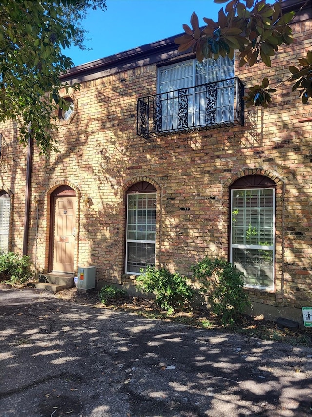 view of property exterior featuring brick siding, central AC, and a balcony
