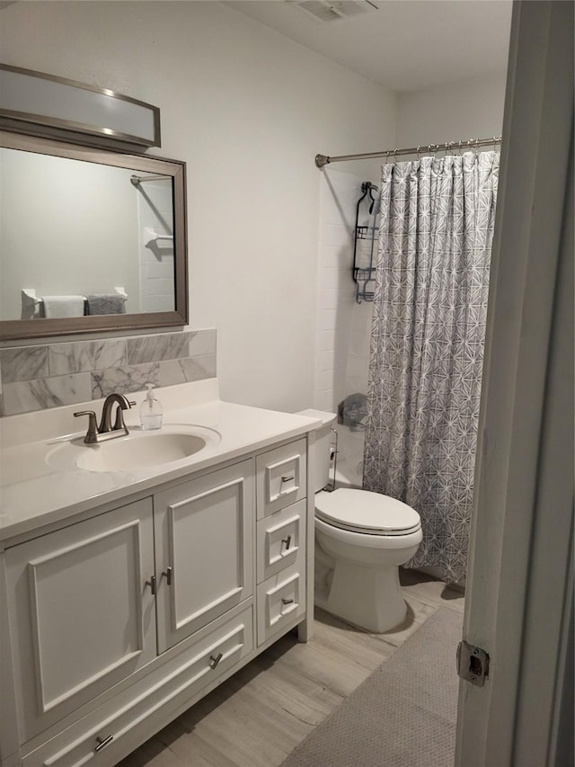 full bath with vanity, toilet, wood finished floors, and visible vents