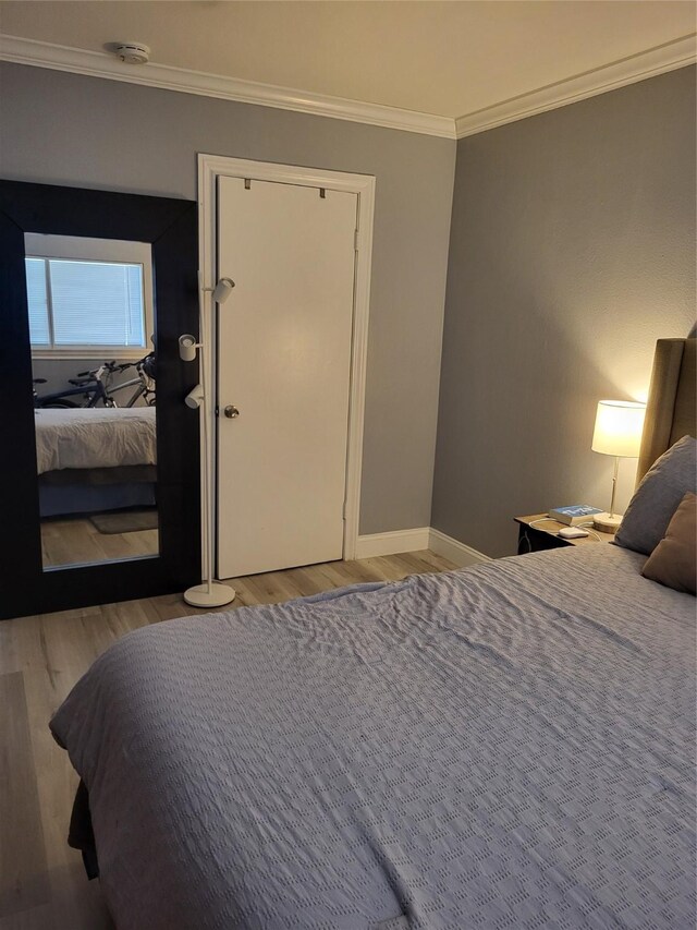 bedroom featuring crown molding, baseboards, and wood finished floors