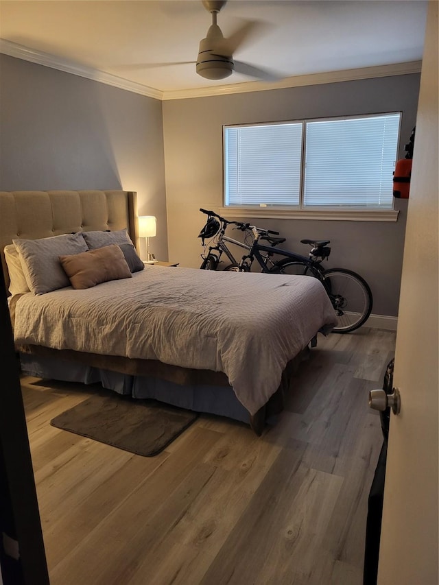 bedroom featuring a ceiling fan, crown molding, baseboards, and wood finished floors