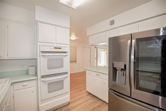 kitchen with light wood-style floors, white double oven, stainless steel refrigerator with ice dispenser, white cabinetry, and visible vents