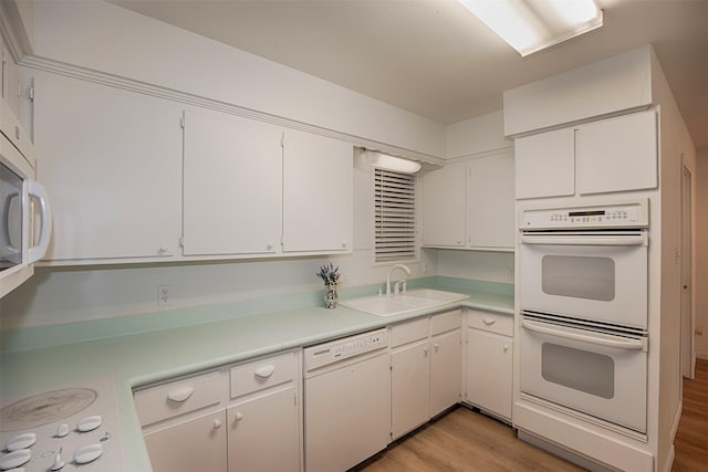 kitchen with light countertops, a sink, white appliances, and light wood-style flooring
