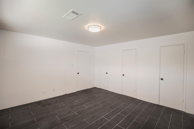 unfurnished bedroom featuring visible vents and dark wood-type flooring