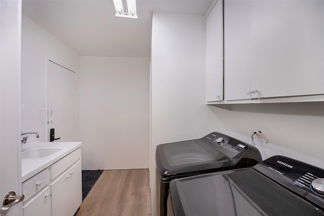 laundry area featuring cabinet space, light wood-type flooring, separate washer and dryer, and a sink
