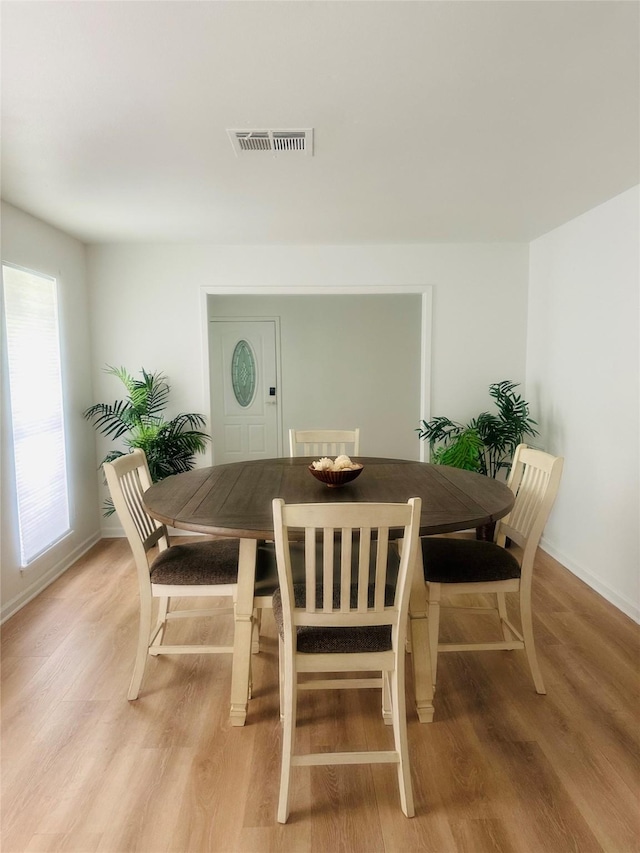 dining room with light wood-type flooring, baseboards, and visible vents