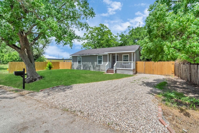 view of front of house with a porch, driveway, fence private yard, and a front yard
