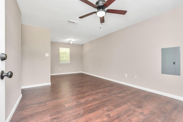 empty room featuring dark wood-type flooring, ceiling fan, electric panel, and visible vents