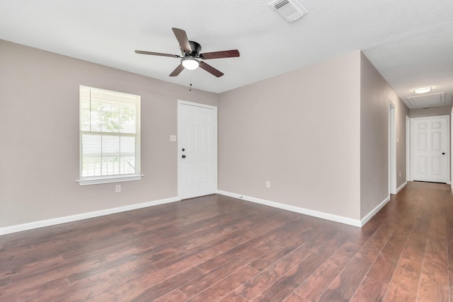 empty room with visible vents, dark wood finished floors, ceiling fan, and baseboards