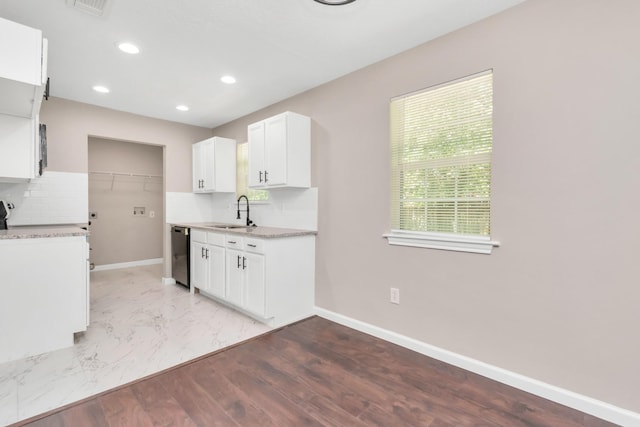kitchen featuring a sink, light countertops, baseboards, tasteful backsplash, and dishwashing machine