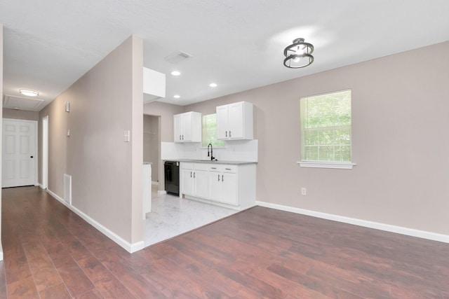 kitchen featuring a sink, dishwasher, white cabinetry, baseboards, and wood finished floors