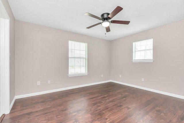 spare room with ceiling fan, dark wood-style floors, and baseboards