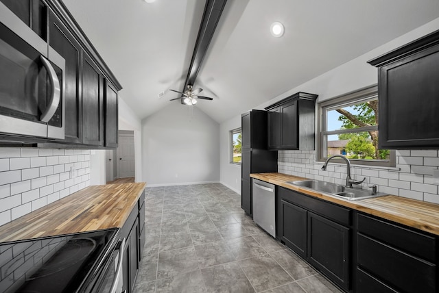 kitchen with tasteful backsplash, a sink, dark cabinetry, wood counters, and stainless steel appliances