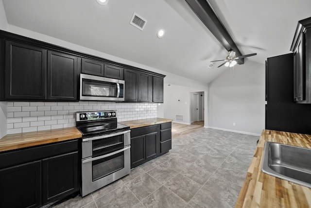 kitchen featuring ceiling fan, dark cabinets, tasteful backsplash, appliances with stainless steel finishes, and wood counters