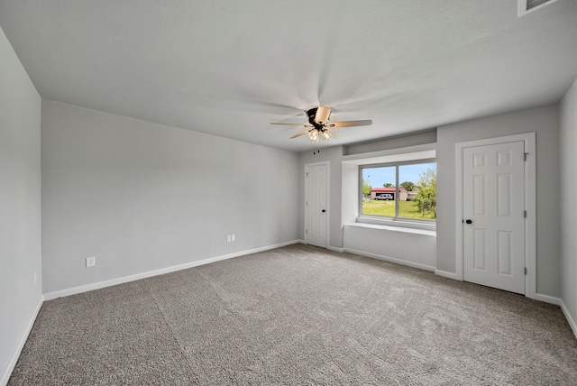 carpeted spare room featuring visible vents, baseboards, and a ceiling fan