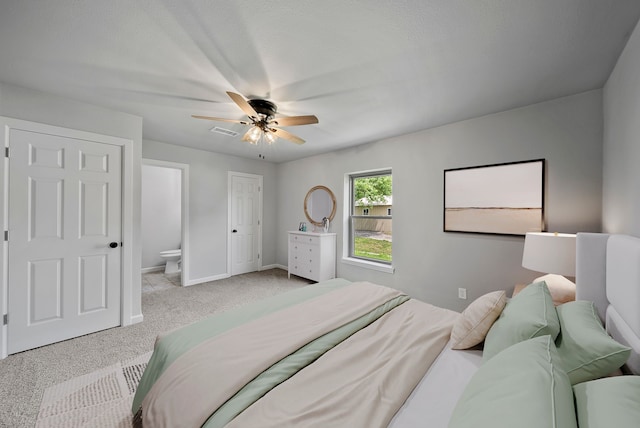 bedroom with ensuite bathroom, a ceiling fan, visible vents, carpet floors, and baseboards