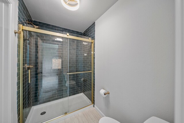 bathroom with toilet, baseboards, and a shower stall