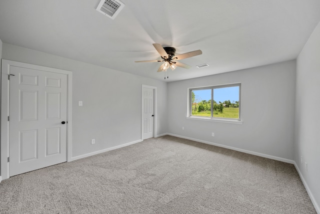 carpeted spare room featuring ceiling fan, baseboards, and visible vents