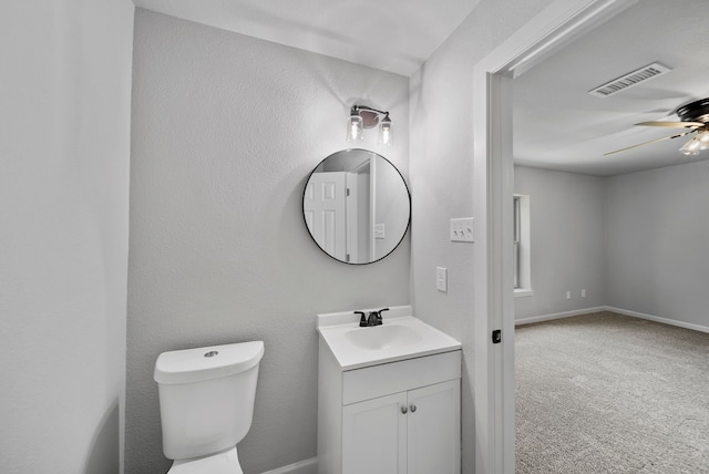 half bath featuring ceiling fan, vanity, visible vents, toilet, and baseboards