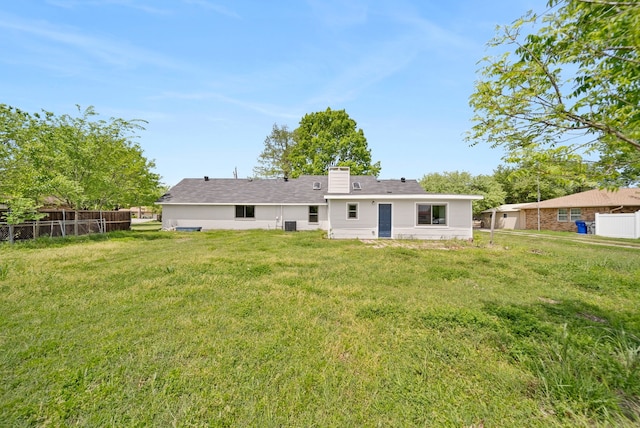 rear view of property with fence and a lawn