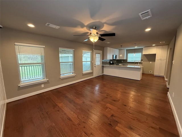 unfurnished living room featuring ceiling fan, visible vents, baseboards, and dark wood-style floors