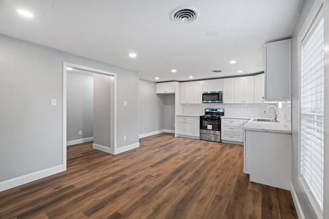 kitchen with visible vents, backsplash, appliances with stainless steel finishes, dark wood-style floors, and a sink