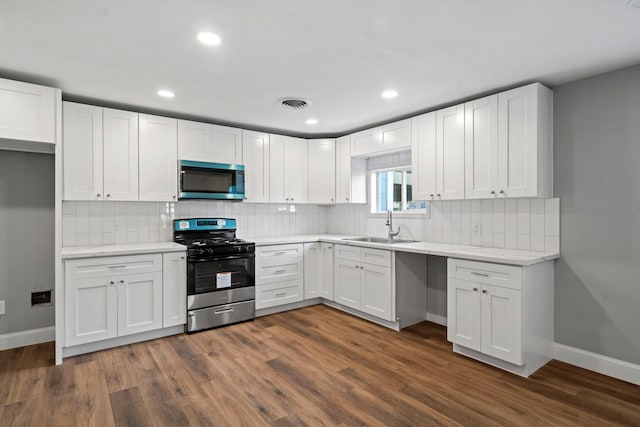 kitchen with stainless steel microwave, visible vents, a sink, range with gas stovetop, and dark wood-style flooring
